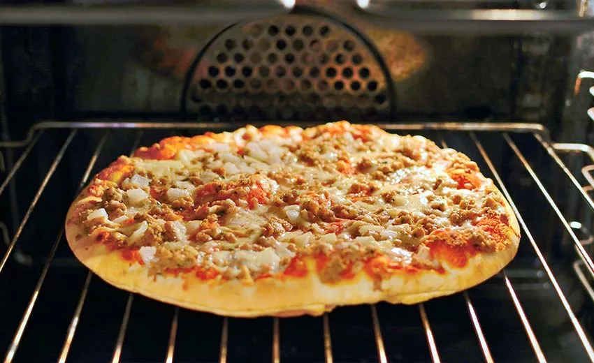 Pizza im Backofen auf Rost kurz bevor sie fertig ist.